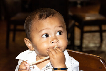 Adorable little Filipino American baby wide-eyed as he eats Udon noodles for the first time
