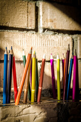 Children wooden crayons in 25 colors on brick wall background