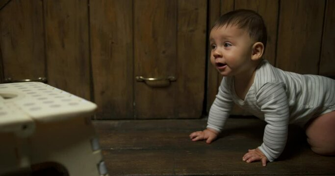 A little baby is crawling towards a foot stool at home and is using it to stand up