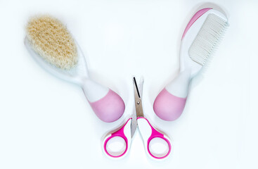 Two baby combs and pink baby scissors, isolated on white
