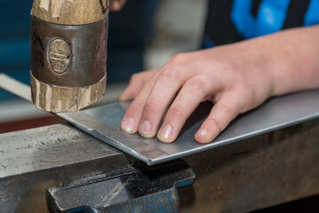Person Folds Sheet Edges With A Mallet - Close-up