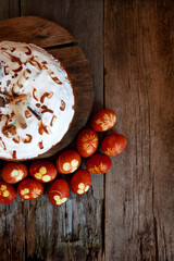 Easter cake and colored eggs. Rustic food on a wooden table. Egg colored with onion peel. Clover and dill leaves pattern. Classic food for the Easter holiday