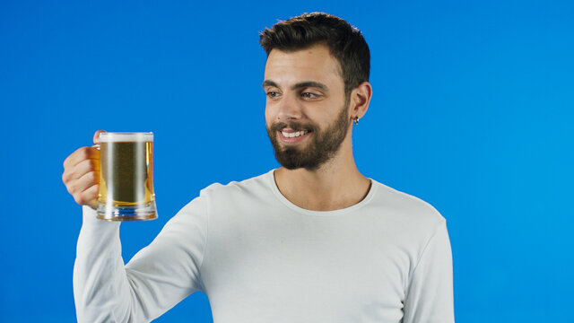 Young man drinking beer, showing beer and smiling at camera.Portrait of young male staring lovingly at beer.
