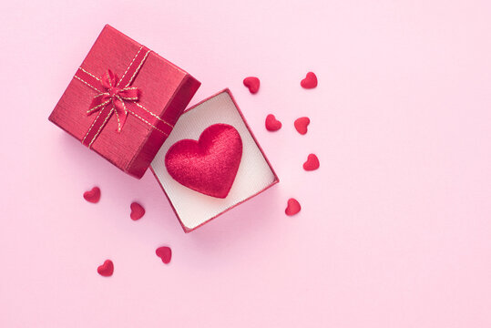 Gift box and red heart on pink background with copy space for love wedding or valentines day