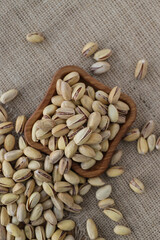 fried pistachios lie in a wooden menagerie scattered around on a wooden table and burlap