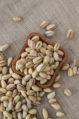 fried pistachios lie in a wooden menagerie scattered around on a wooden table and burlap