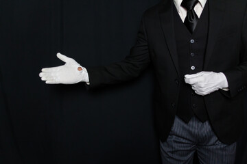 Black and White Portrait of Butler or Servant in Dark Suit and White Gloves with a Welcoming Gesture. Service Industry. Professional Hospitality and Courtesy. Formal White Glove Service.