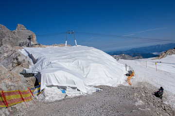 A glacier covered with white sheet to protect it from melting during summer season. White blankets...