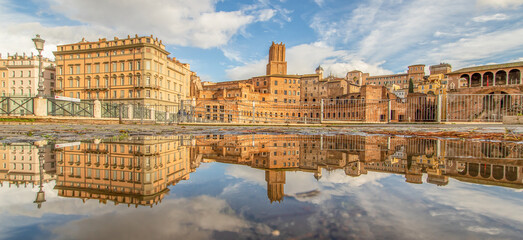 Fototapeta na wymiar Rome, Italy - in Winter time, frequent rain showers create pools in which the wonderful Old Town of Rome reflect like in a mirror. Here in particular Via dei Fori Imperiali