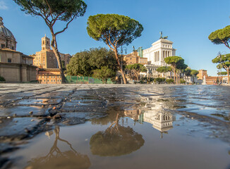 Rome, Italy - in Winter time, frequent rain showers create pools in which the wonderful Old Town of Rome reflect like in a mirror. Here in particular Via dei Fori Imperiali