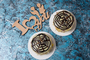 Two cakes with almond chips, chocolate, icing and cream on a blue background, for lovers on the holiday of February 14