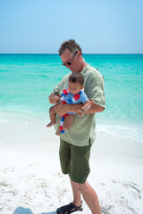 father and son on the beach before the crystal waters on a sunny summer day