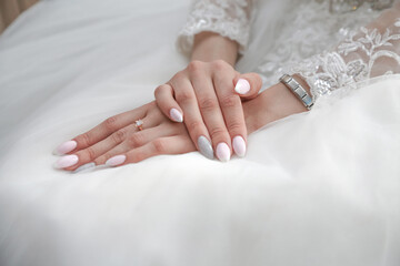 the bride folded her hands with a beautiful manicure on the wedding dress