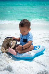 Filipino American baby with hat playing on the beach 