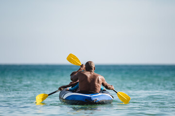 black man kayaking with son on the sea