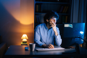 Side view of thoughtful young man looking at camera and starts typing on wireless keyboard while...