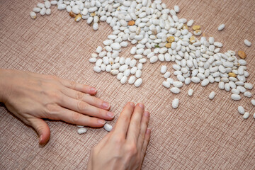The girl selects and cleans the beans on the kitchen table. Food preparation.