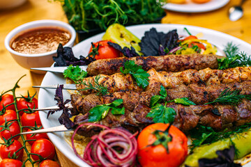 assorted kebabs with grilled vegetables and spicy sauce on a decorated table