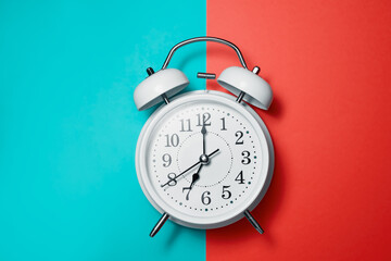 Clock alarm in vintage style on green red background flat lay.