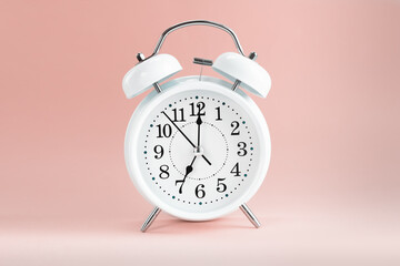 White clock alarm in vintage style on color background pastel shades