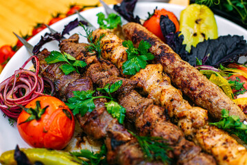 assorted kebabs with grilled vegetables and spicy sauce on a decorated table