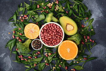 peanut beans in a bowl, sliced avocado and orange halves lie on spinach leaves
