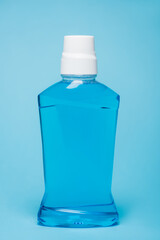 Bottle of mouthwash with white cap on blue background