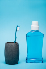 Bottle of mouthwash near toothbrush on blue background