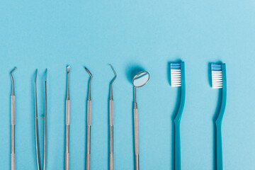 Top view of stainless dental tools and toothbrushes on blue background