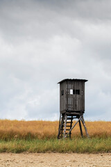 Lonely high seat stands in a wide field, with a dramatic sky