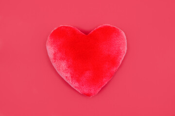 Plush red heart on red background, close-up