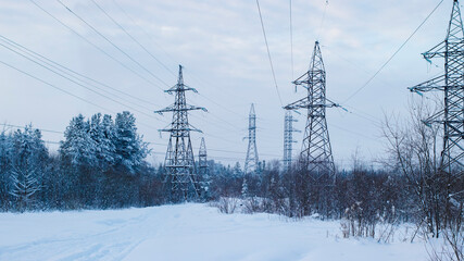 Power transmission lines in coniferous forest in winter. Winter landscape with high voltage power lines.