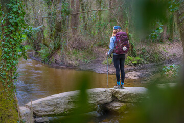Obraz premium Pilgrim Girl Hiking on a Stone Bridge in Galicia Spain along the Way of St James Camino de Santiago Trail
