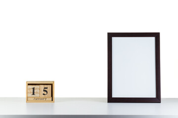 Wooden calendar 15 January with frame for photo on white table and background