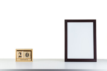 Wooden calendar 20 January with frame for photo on white table and background