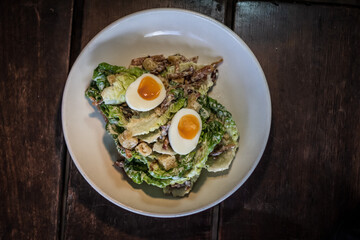 Classic Fresh Caesar Salad with cos lettuce, bacon, garlic croutons, hard boiled egg, Caesar dressing, parmesan cheese