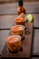 Bloody mary oysters shooters in wood plate with lemon and spicy sauce seafood