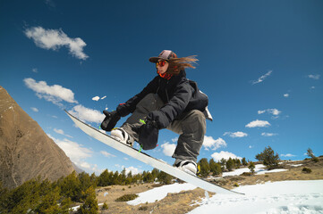 Woman athlete snowboarder flies after jumping from kicker doing trick