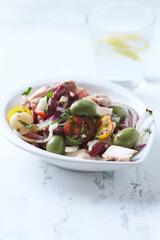 Salad with tuna, green olives and cherry tomatoes. Bright wooden background. Close up. 