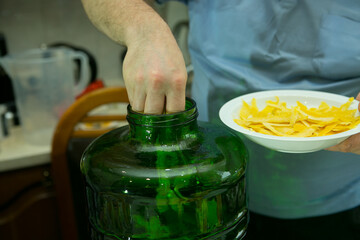 The process of making limoncello lemon liqueur at home. A man adds prepared fresh lemon zest to a...