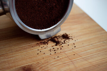 .a coffee horn filled with ground coffee lies sideways on a wooden board, photographed close-up