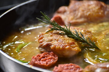 Process of preparing paella on a frying pan with rosemary, chorizo and chicken