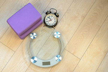 Bathroom scales and alarm clock and yoga bricks. Fitness for weight loss.