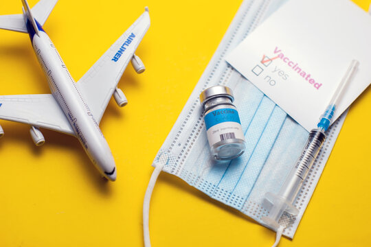 Travel During Covid-19 Pandemic. Airplane Model, Protection Medical Mask, Vaccine, Syringe And Vaccinated Card With 