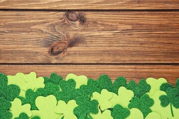 Decorative clover leaves on wooden background, flat lay with space for text. St. Patrick's Day...