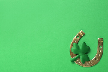 Decorative clover leaf and horseshoe on green background, flat lay with space for text. St....