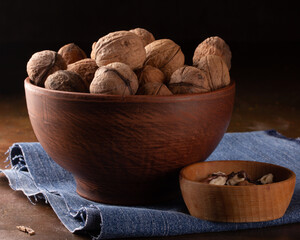 Whole and peeled walnuts in ceramic and wooden dishes