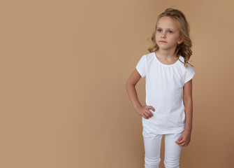 Front portrait of pretty little girl with wavy hair, dressed in white clothes. Copy space.