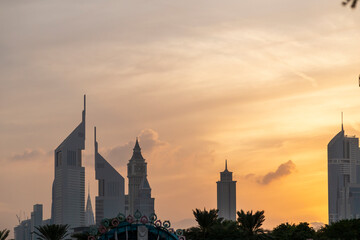 UAE, DUBAI, CIRCA 2021: Dubai Financial center district. View of The Jumeirah Emirates Towers in DIFC and Burj Khalifa. Sunset view with cloudy sky