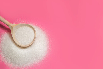 spoon of white sugar on pink background copy space